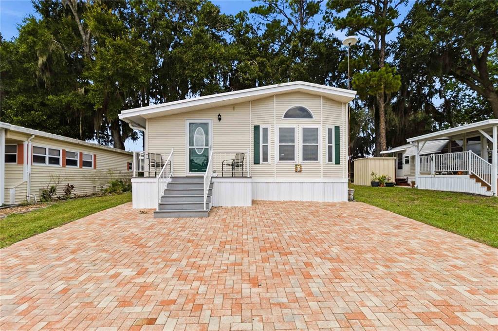 A single-story manufactured home with light siding and a brick paver driveway — 67 CITRUS RIDGE DRIVE, DAVENPORT, FL