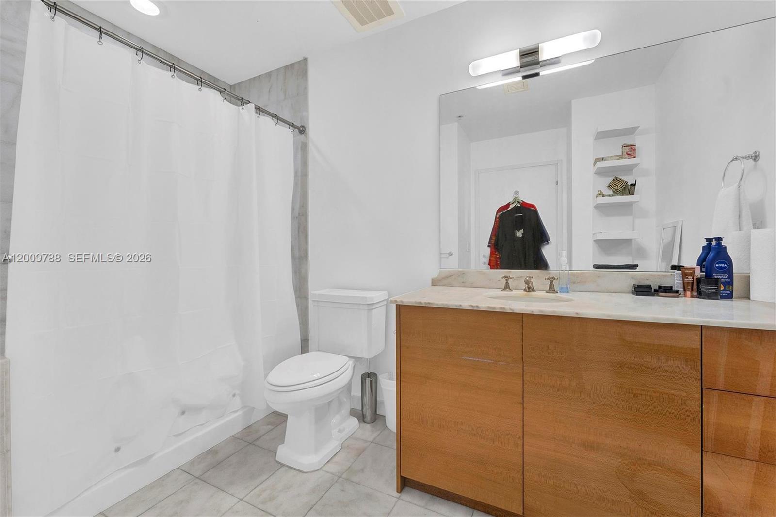 This bathroom features a wood vanity with a stone countertop, a toilet, and a shower — 50 S Pointe Dr # 2102, Miami Beach FL 33139, MIAMI BEACH, FL