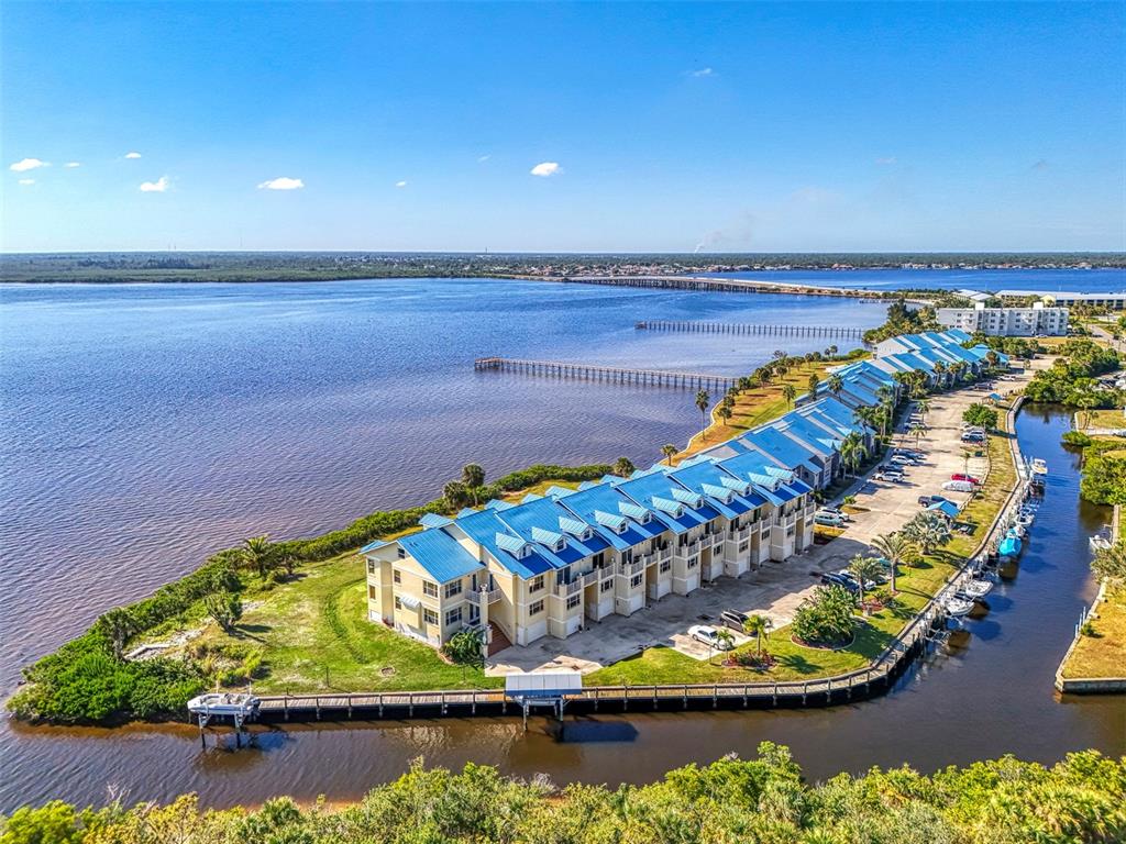 An aerial view shows a row of waterfront townhomes with blue roofs along a bay — 4410 WARREN AVENUE UNIT 504, PORT CHARLOTTE, FL