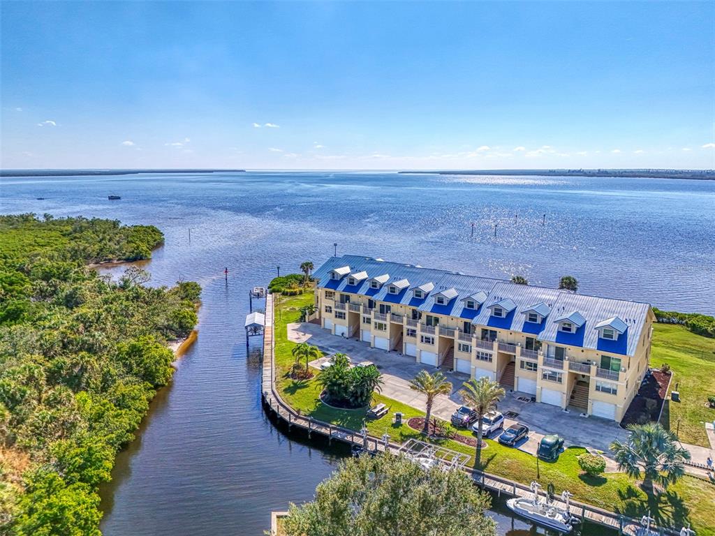 An aerial view shows a multi-story waterfront townhouse complex with a dock and boat slips — 4410 WARREN AVENUE UNIT 504, PORT CHARLOTTE, FL