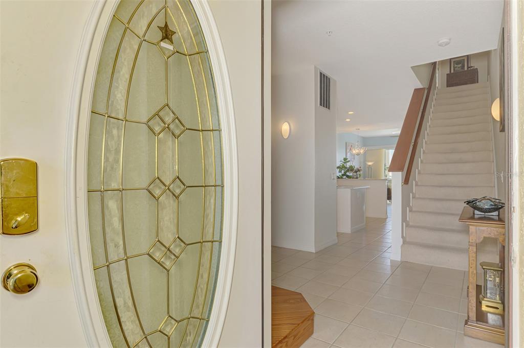 A view through an open front door showing a tiled entryway and a carpeted staircase — 4410 WARREN AVENUE UNIT 504, PORT CHARLOTTE, FL