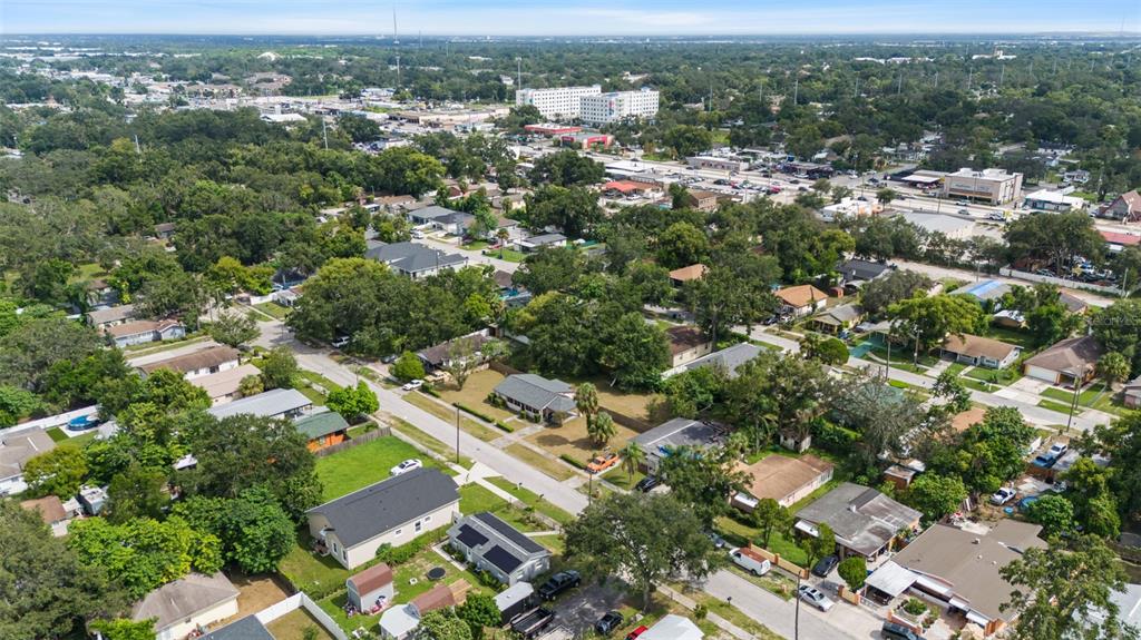 An aerial view shows a suburban neighborhood with houses, trees, and nearby commercial buildings — 3415 DELEUIL AVENUE, TAMPA, FL