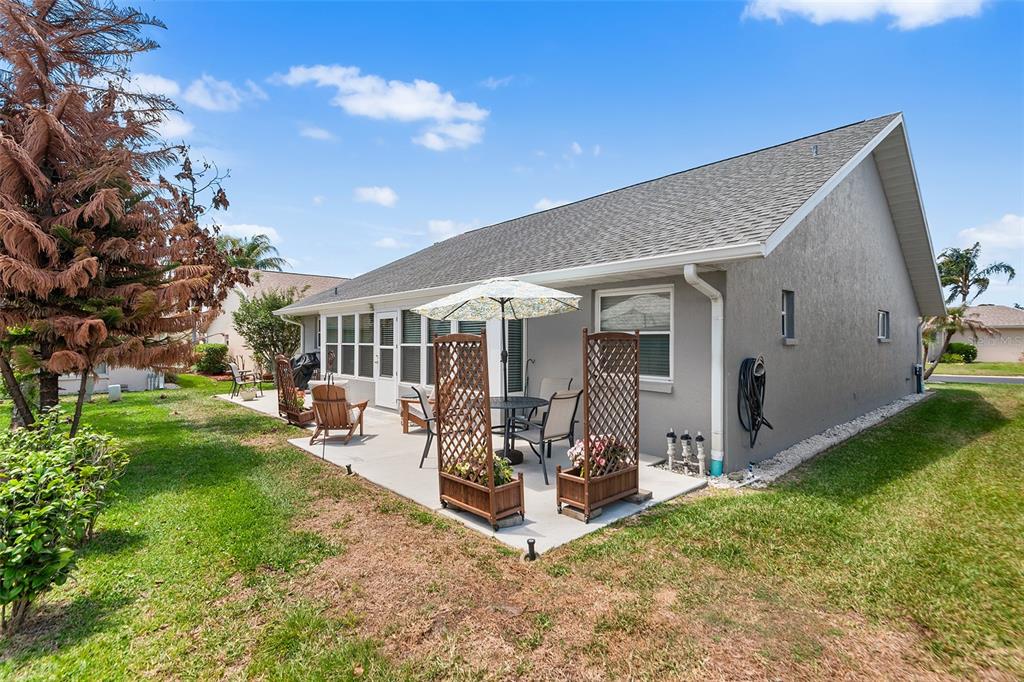 A concrete patio with outdoor furniture and lattice planters sits behind a gray house — 510 EASTLAKE DR, HAINES CITY, FL