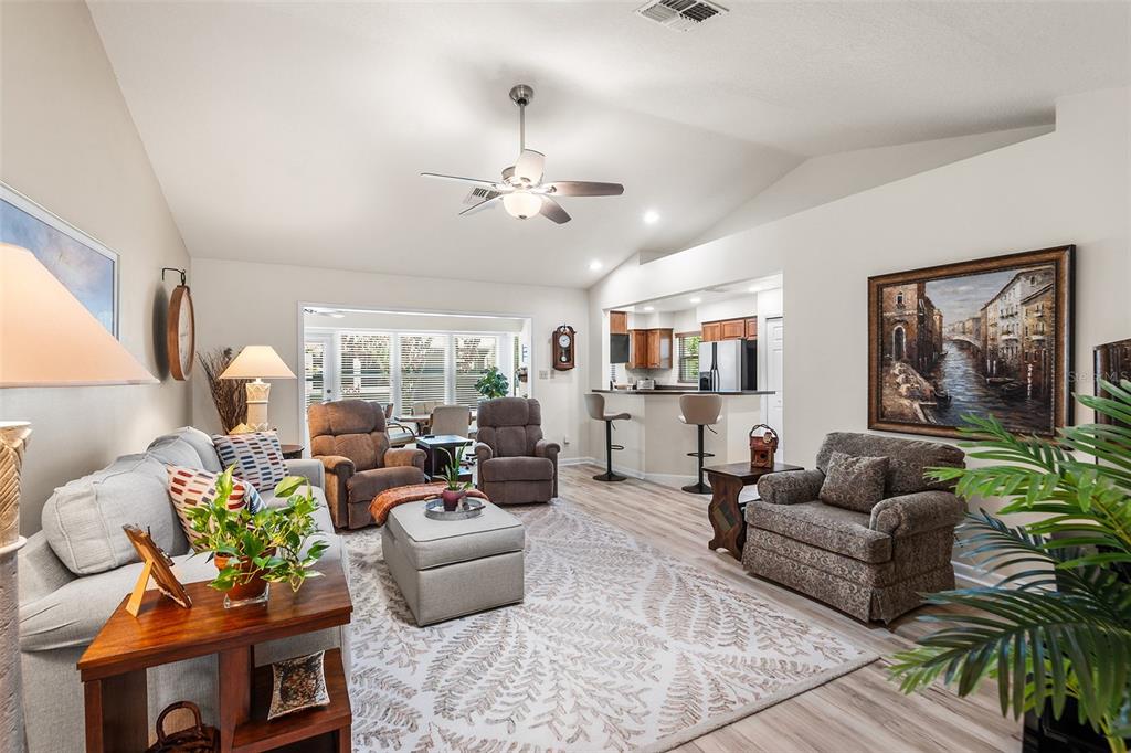 A living room with vaulted ceilings, a ceiling fan, and an open kitchen with bar seating — 510 EASTLAKE DR, HAINES CITY, FL
