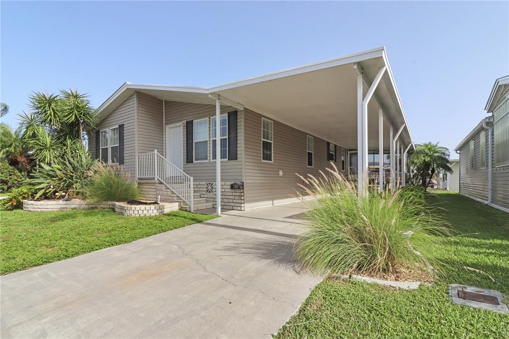 A single-story house with beige siding, a concrete driveway, and a large attached carport — 2100 KINGS HIGHWAY UNIT 742, PORT CHARLOTTE, FL