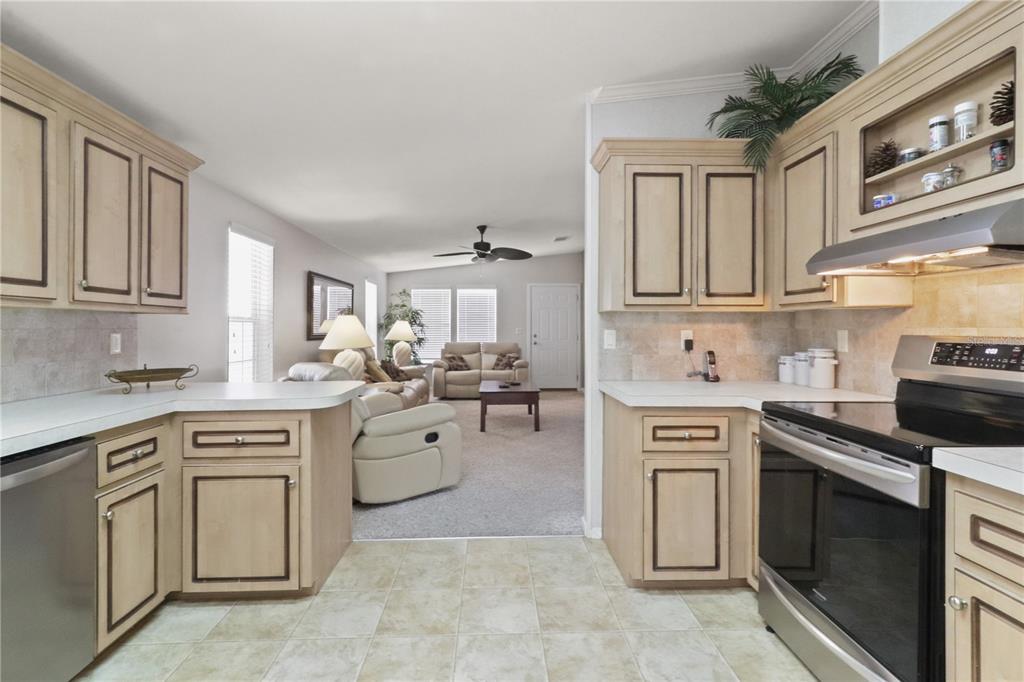 A kitchen with light wood cabinets and tile flooring opens into a carpeted living area — 2100 KINGS HIGHWAY UNIT 742, PORT CHARLOTTE, FL