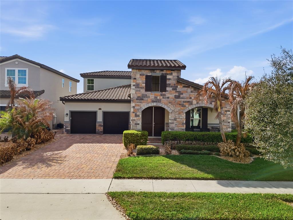 A two-story house with a stone facade, tile roof, and a brick-paved driveway — 1646 HOLCOMB CREEK STREET, WINTER GARDEN, FL