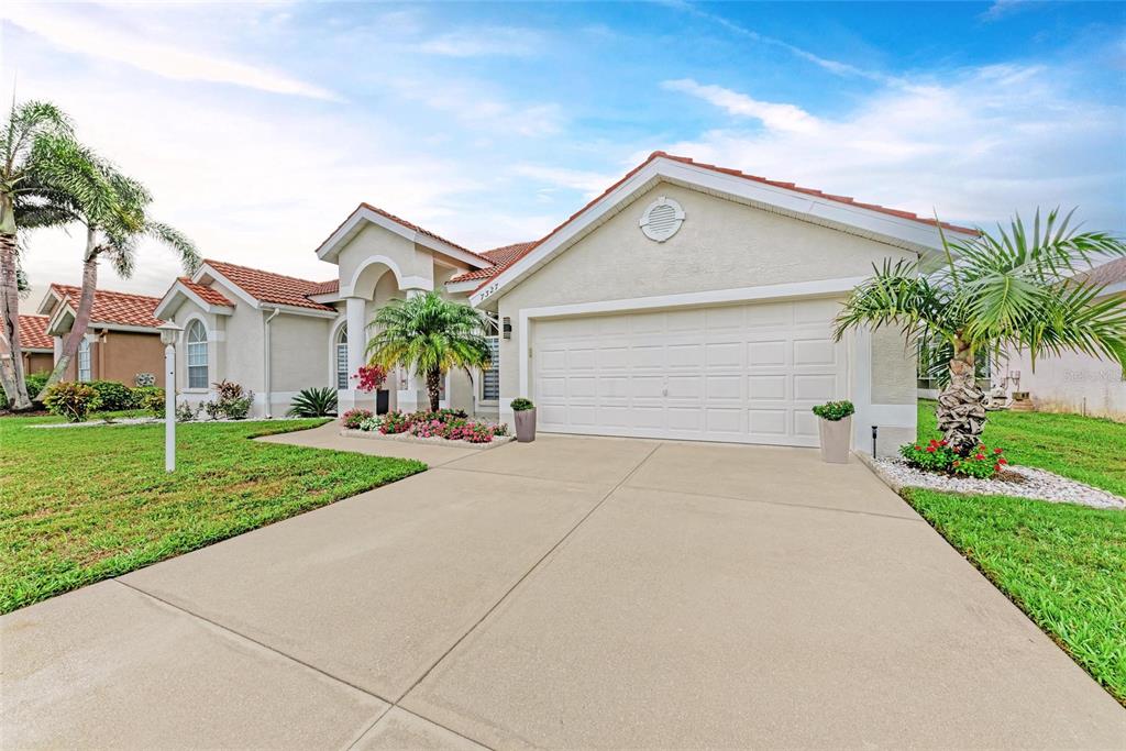 A single-story house with a white garage, tiled roof, and palm trees in the front yard — 7327 38TH COURT EAST, SARASOTA, FL