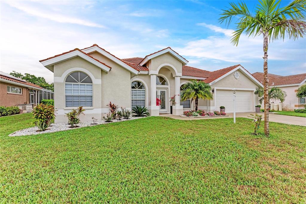 A single-story stucco house with a tiled roof, arched windows, and a front lawn — 7327 38TH COURT EAST, SARASOTA, FL