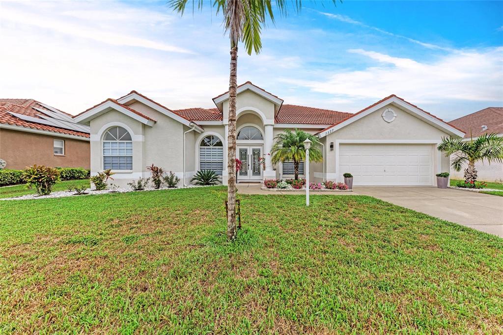 A single-story suburban house with a tiled roof, white stucco exterior, and a two-car garage — 7327 38TH COURT EAST, SARASOTA, FL