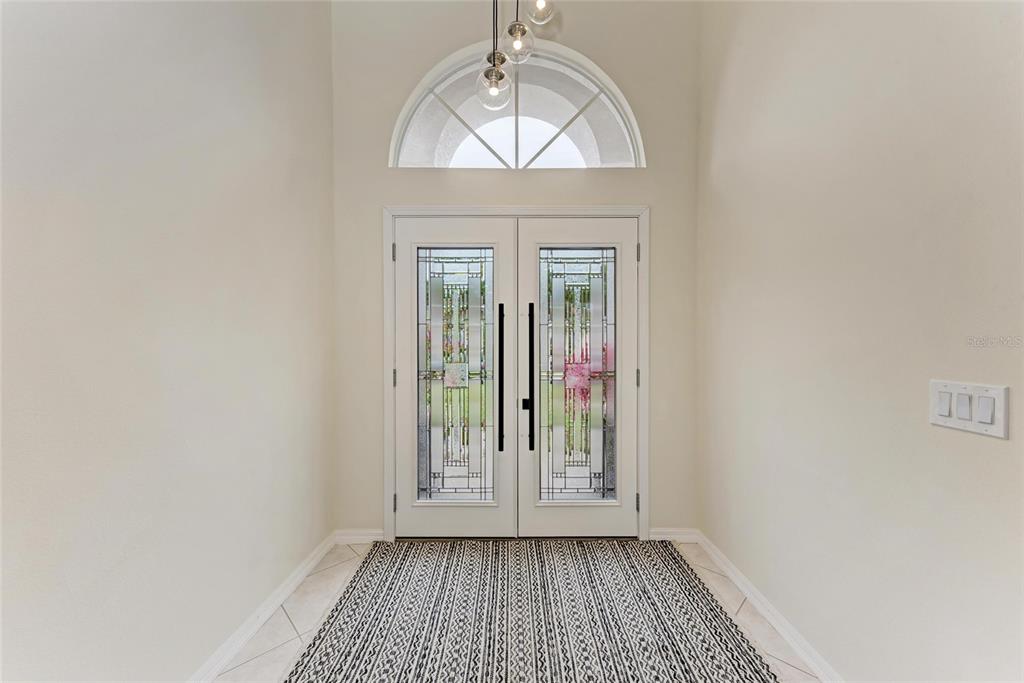 A bright entryway features double glass-paneled doors, a semi-circular transom window, and a patterned rug — 7327 38TH COURT EAST, SARASOTA, FL