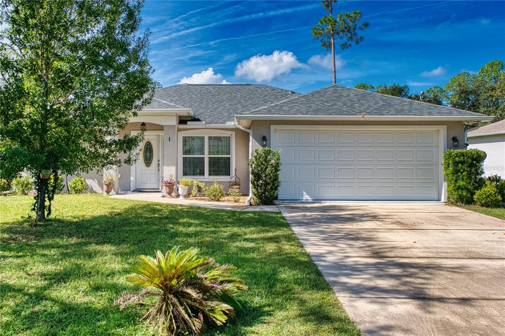 A single-story suburban house with a gray shingled roof, white garage, and front lawn — 1 LLOSEE COURT, PALM COAST, FL