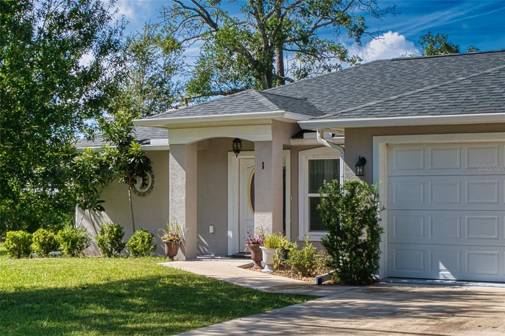 A single-story house with a gray shingled roof, beige stucco exterior, and a front garage — 1 LLOSEE COURT, PALM COAST, FL