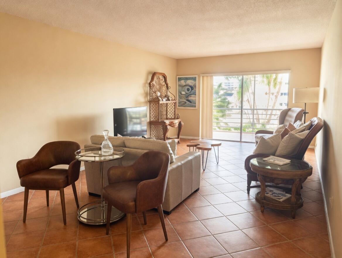 A living room with tile floors, a sofa, armchairs, and a balcony with palm trees — 1430 S Lakeside Drive # 22, FL 33460, FL