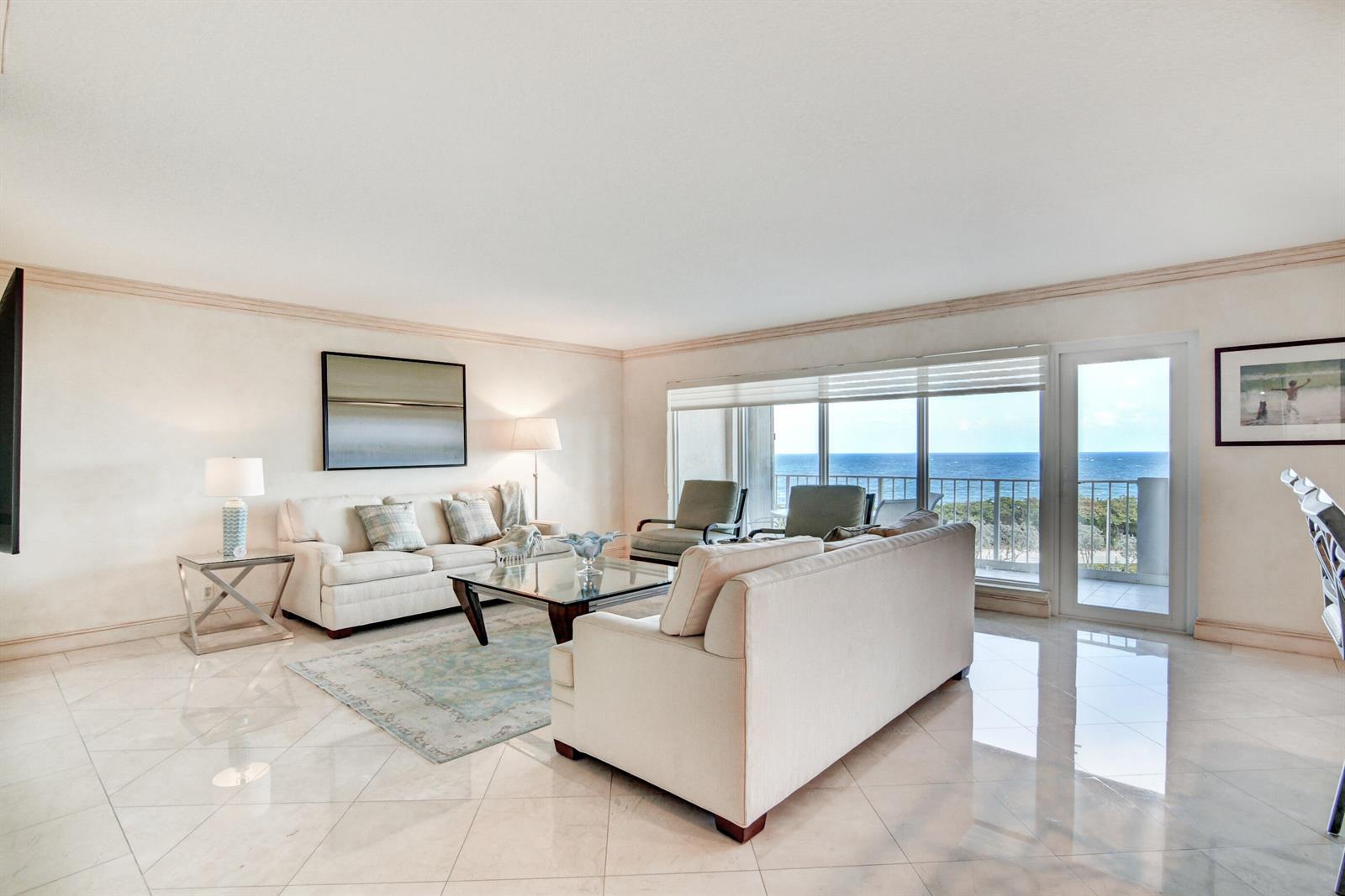 A bright living room features light tile floors, two sofas, and a balcony overlooking the ocean — 4301 N Ocean Boulevard # 607, Boca Raton FL 33431, BOCA RATON, FL