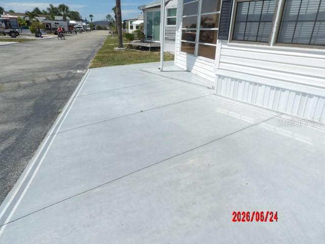 A concrete driveway leads to the side entrance of a white mobile home — 1475 FLAMINGO DRIVE UNIT 105, ENGLEWOOD, FL
