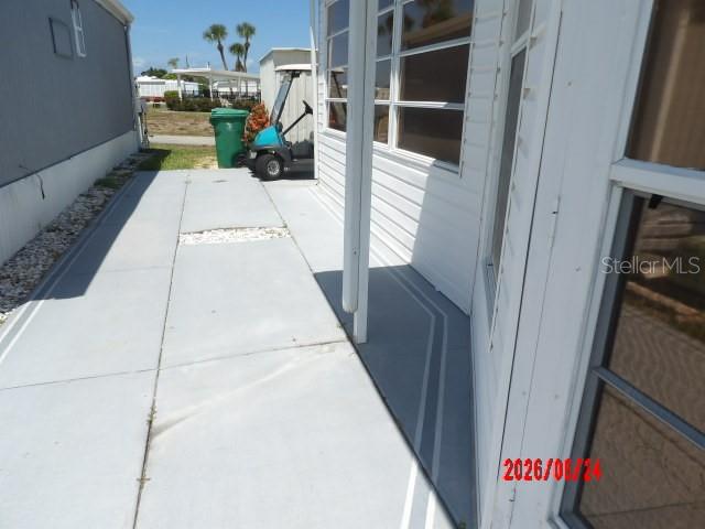 A concrete patio area beside a mobile home with a golf cart parked nearby — 1475 FLAMINGO DRIVE UNIT 105, ENGLEWOOD, FL