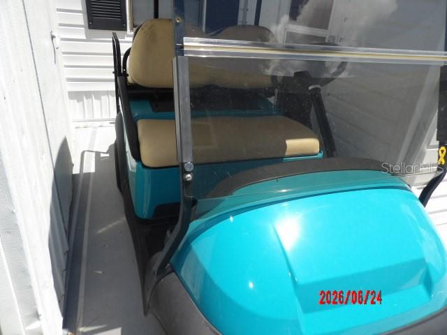 A teal golf cart with tan seats is parked on a concrete patio — 1475 FLAMINGO DRIVE UNIT 105, ENGLEWOOD, FL
