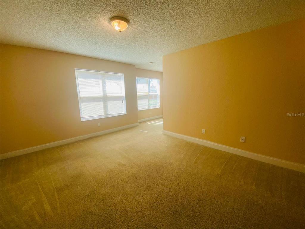 An empty room features beige carpet, yellow walls, and two windows with white blinds — 5773 GATLIN AVENUE UNIT 616, ORLANDO, FL