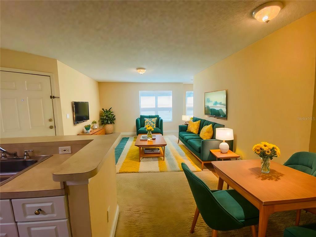 A living and dining area features a green sofa, matching chairs, and a yellow rug — 5773 GATLIN AVENUE UNIT 616, ORLANDO, FL