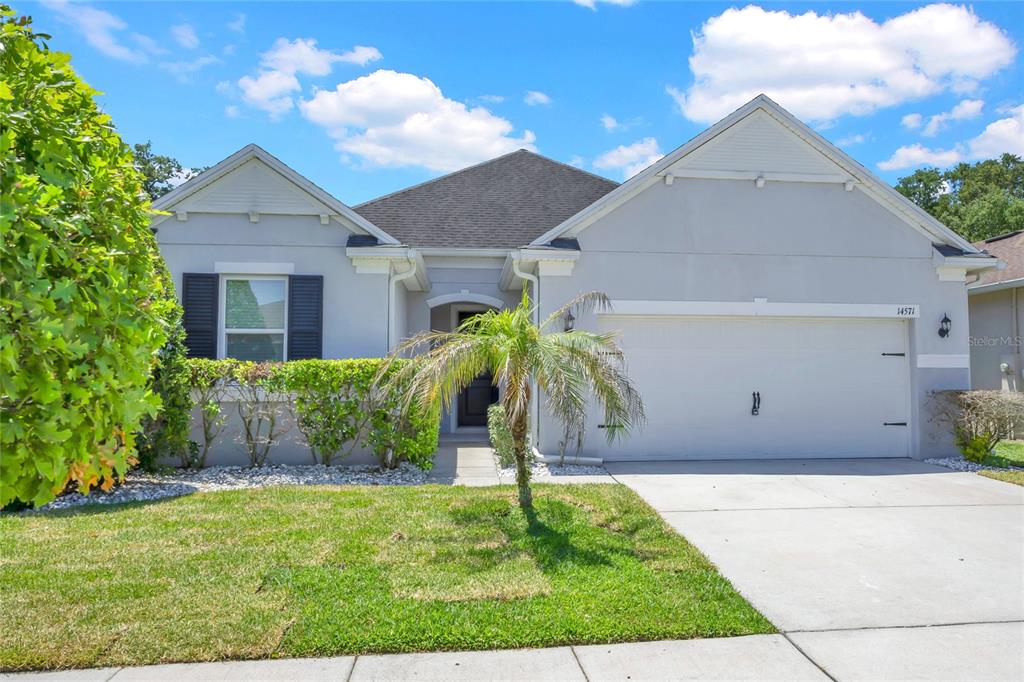 A single-story house features a gray stucco exterior, a two-car garage, and a small palm tree — 14571 WARD ROAD, ORLANDO, FL