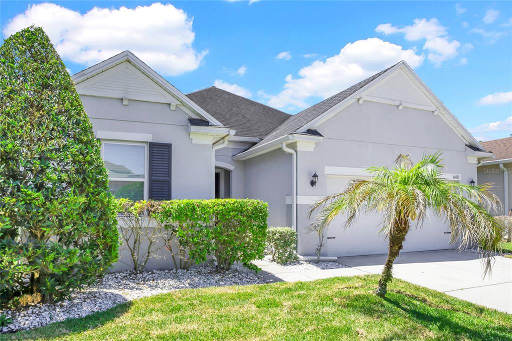 A single-story house with a gray stucco exterior, a two-car garage, and a palm tree — 14571 WARD ROAD, ORLANDO, FL