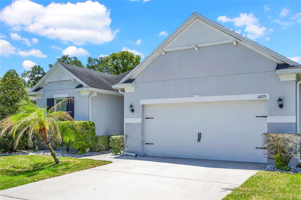 A light gray single-story house features a two-car garage and a small palm tree — 14571 WARD ROAD, ORLANDO, FL