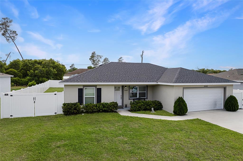 A single-story house with a gray roof, stucco exterior, and a two-car garage — 15458 SW 23RD COURT ROAD, OCALA, FL