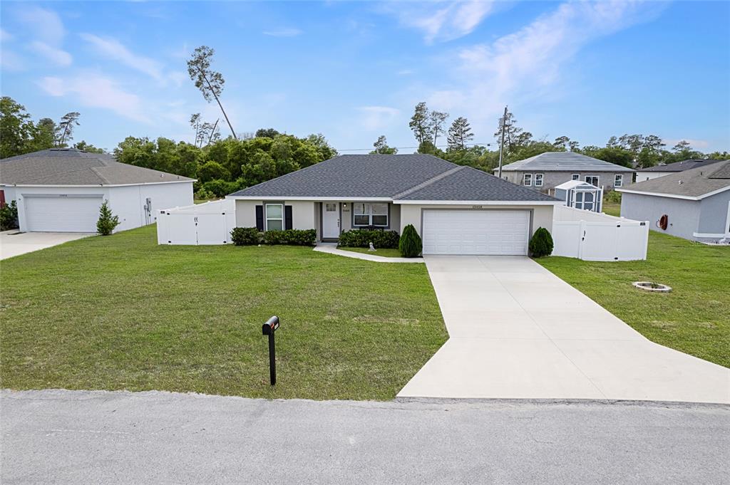 A single-story suburban house features a gray roof, white garage, and a fenced backyard — 15458 SW 23RD COURT ROAD, OCALA, FL