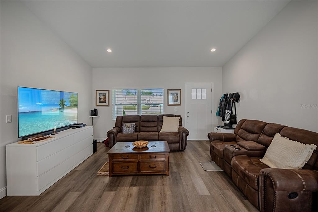 A living room features brown leather sofas, a wooden coffee table, and a white media console — 15458 SW 23RD COURT ROAD, OCALA, FL