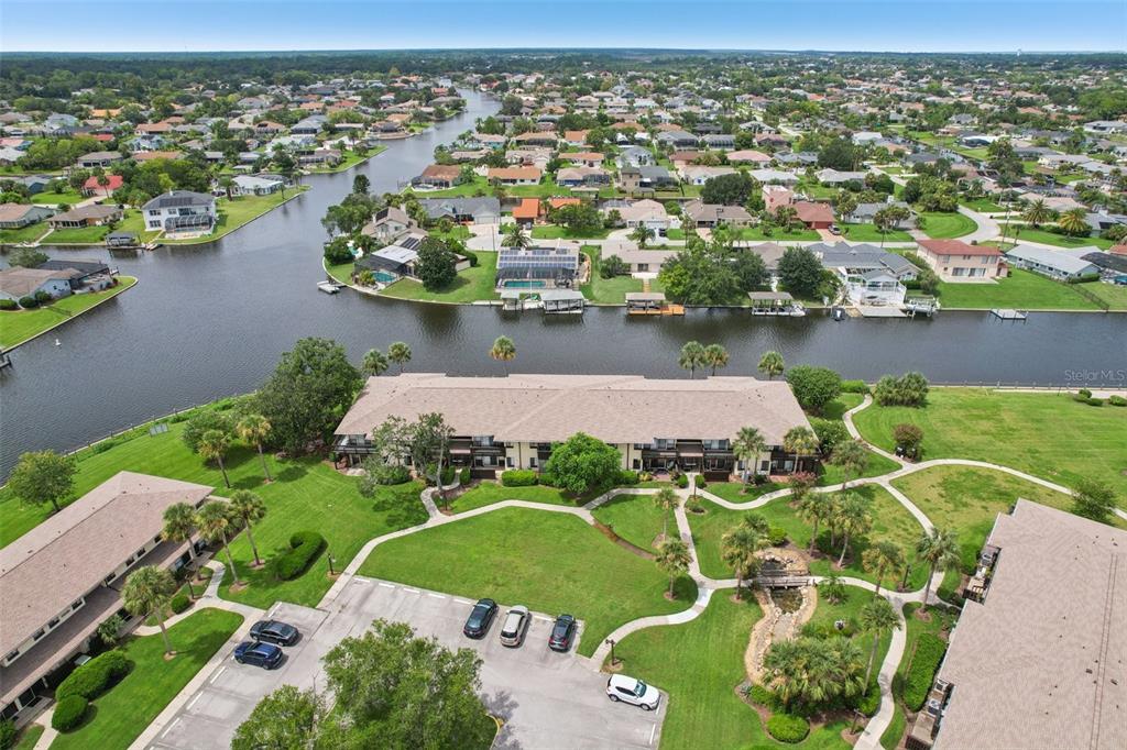 An aerial view shows a multi-unit residential building with a canal and surrounding neighborhood — 46 CLUB HOUSE DRIVE UNIT 108, PALM COAST, FL
