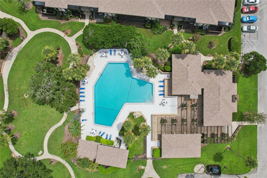An aerial view shows a swimming pool, a clubhouse with a pergola, and surrounding landscaping — 46 CLUB HOUSE DRIVE UNIT 108, PALM COAST, FL
