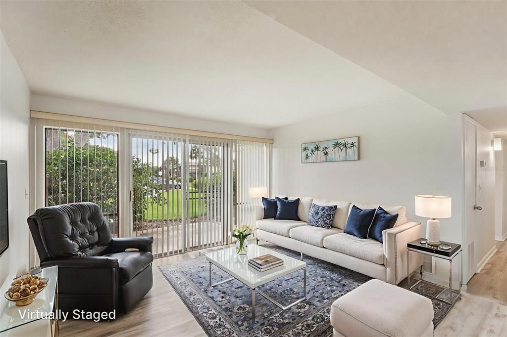 A living room with a sofa, armchair, coffee table, and sliding glass doors to a patio — 46 CLUB HOUSE DRIVE UNIT 108, PALM COAST, FL