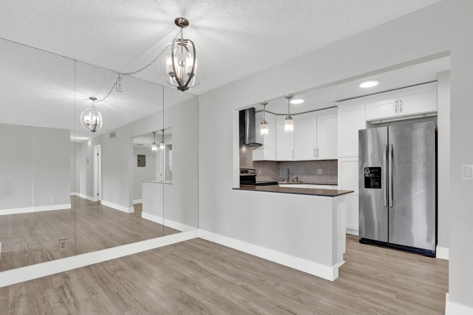 A kitchen with white cabinets and stainless steel appliances opens to a dining area — 715 Sunny Pine Way # B1, FL 33415, FL