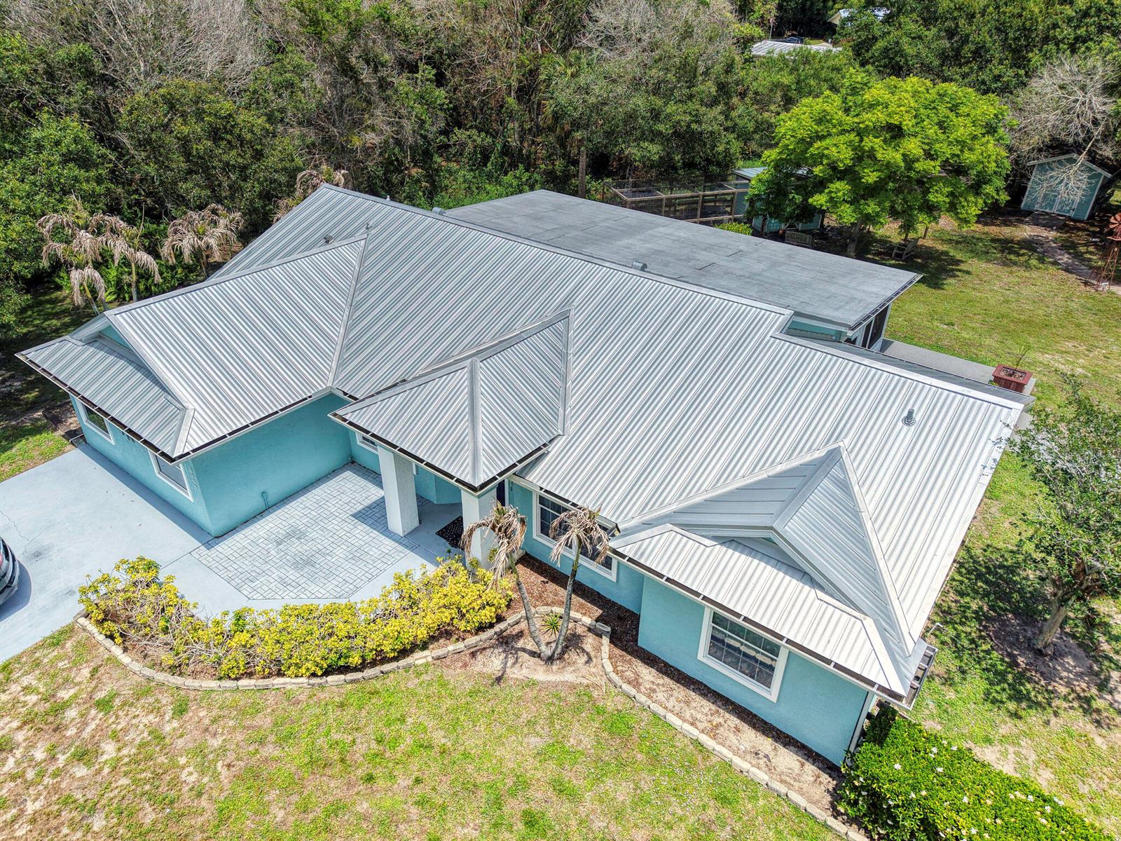 An aerial view of a light blue house with a metal roof and paved entryway — 5700 Oleander Avenue, Fort Pierce FL 34982, FORT PIERCE, FL