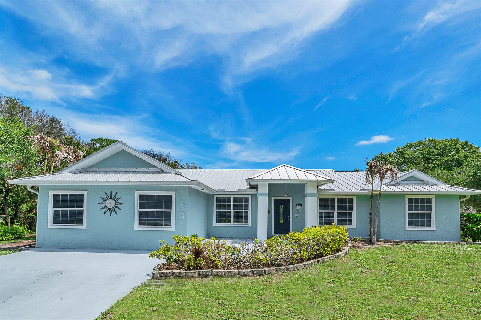 A light blue single-story house with a metal roof and a front garden bed — 5700 Oleander Avenue, Fort Pierce FL 34982, FORT PIERCE, FL