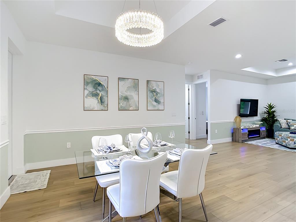 A dining area features a glass table, white chairs, a crystal chandelier, and wall art — 4586 MAURBACH TERRACE, NORTH PORT, FL