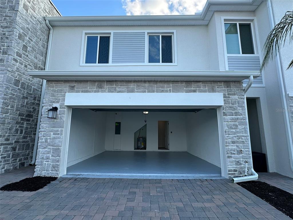 A two-story townhouse exterior features a stone facade, a two-car garage, and a paved driveway — 225 BOGEY DRIVE, DAVENPORT, FL