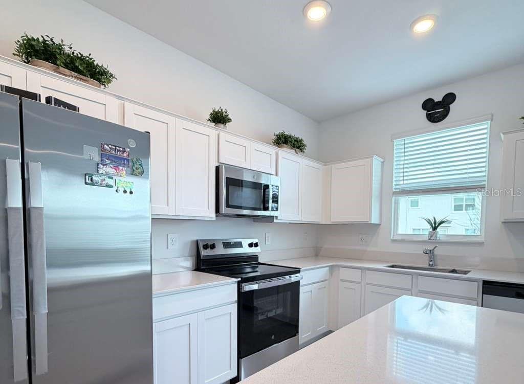 A kitchen features white cabinets, stainless steel appliances, and a white quartz countertop island — 225 BOGEY DRIVE, DAVENPORT, FL