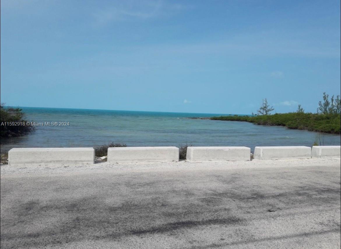 A view of the ocean from a roadside with concrete barriers and mangrove vegetation — DOCTORS CREEK JPOSIAH TANTAILS, LONG ISLAND BAHAMAS, NA, NA