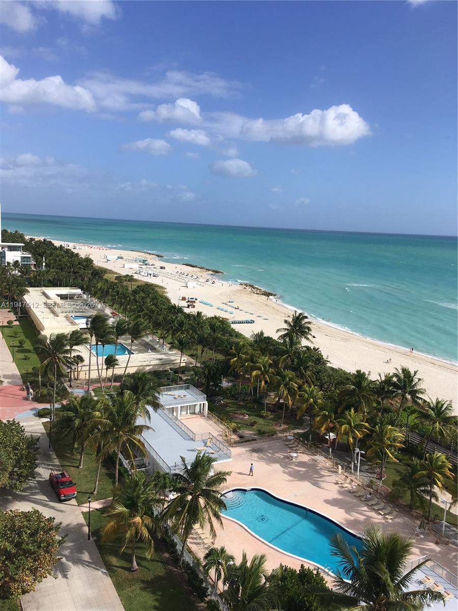 An elevated view of a beach, palm trees, and two swimming pools — 2625 Collins Ave # 1407, Miami Beach FL 33140, MIAMI BEACH, FL