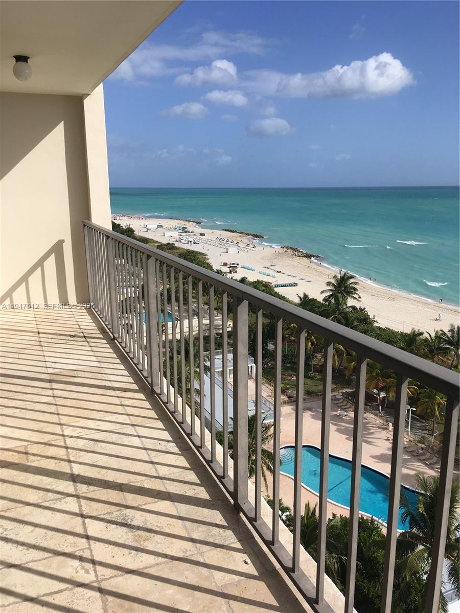 A high-rise balcony with a metal railing overlooks a swimming pool and the ocean beach — 2625 Collins Ave # 1407, Miami Beach FL 33140, MIAMI BEACH, FL