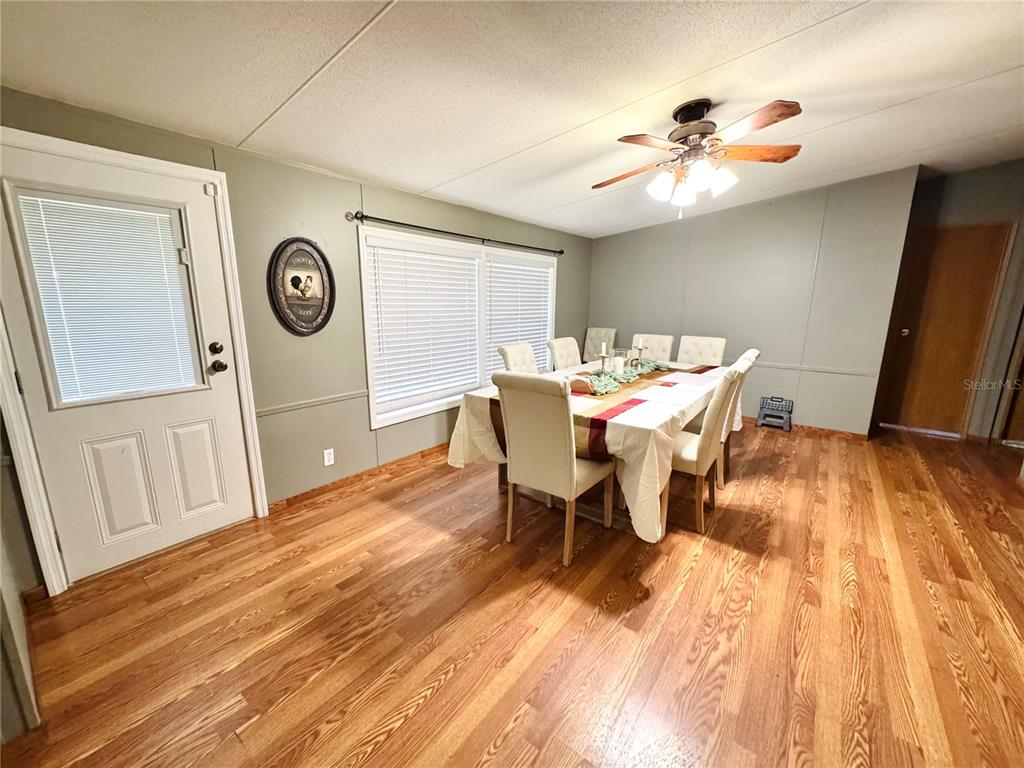A kitchen with white cabinets, a central island, and wood-look flooring opens to a dining area — 713 SULTENFUSS ROAD, BABSON PARK, FL