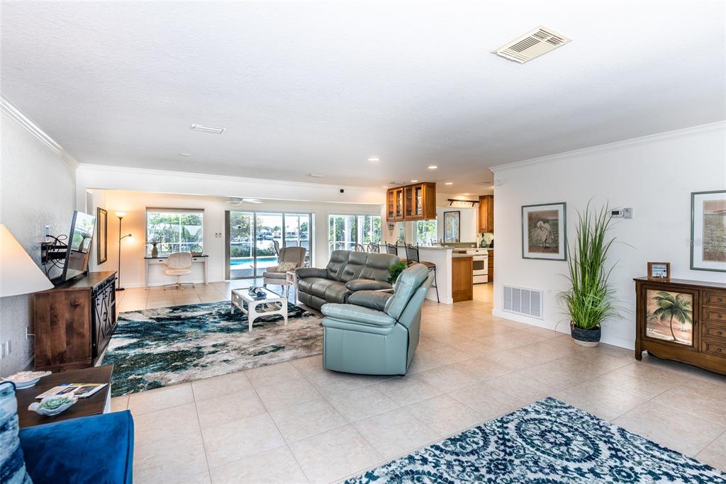 A spacious living room with tile floors, a blue area rug, and an open kitchen — 129 COUSLEY DRIVE SE, PORT CHARLOTTE, FL