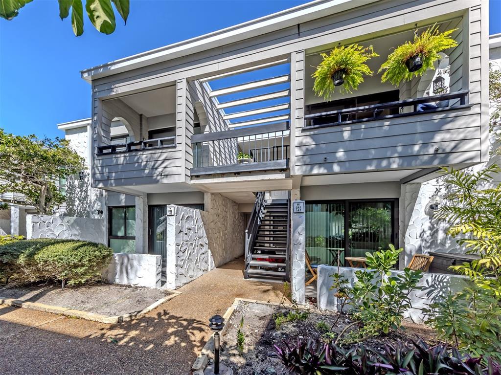 A two-story building exterior features gray horizontal siding, stone accents, and an outdoor staircase — 1555 TARPON CENTER DRIVE UNIT 242, VENICE, FL