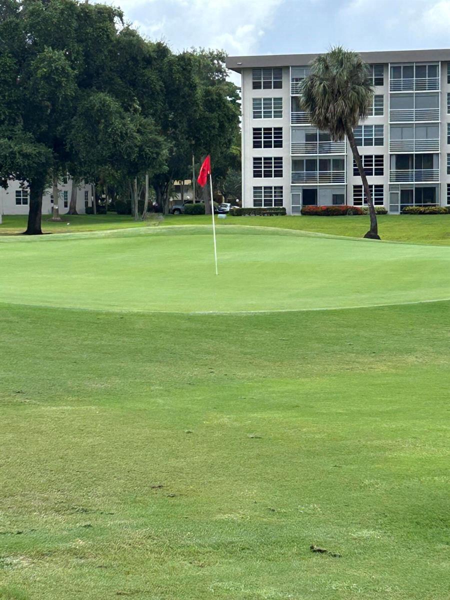 A red flag marks a golf course green in front of a multi-story apartment building — 3520 Oaks Way # 110, Pompano Beach FL 33069, POMPANO BEACH, FL