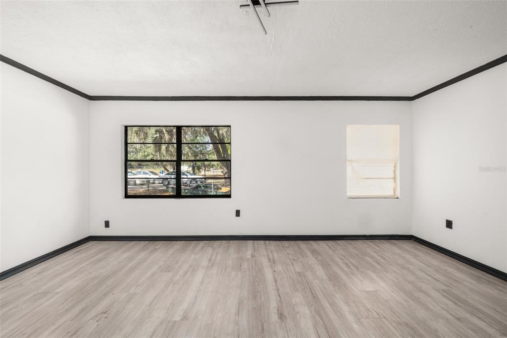 An empty room with white walls, dark trim, and light wood-look flooring — 1628 WIGHTMAN AVENUE, SEBRING, FL