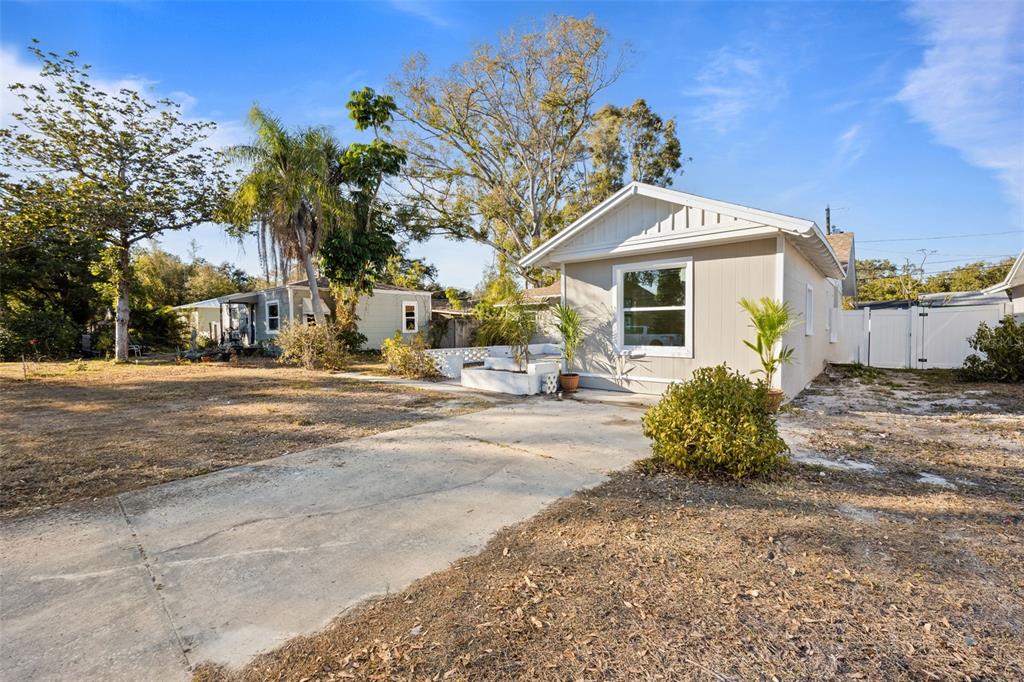 A light-colored single-story house features a concrete driveway, a small front yard, and landscaping — 3821 6TH AVENUE N, ST PETERSBURG, FL