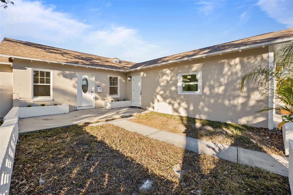 The exterior of a single-story house features a tan facade, two doors, and a walkway — 3821 6TH AVENUE N, ST PETERSBURG, FL