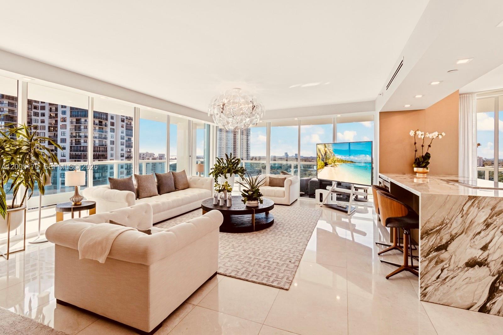A bright living room features white sofas, a marble kitchen island, and floor-to-ceiling windows — 2127 Brickell Ave # 1505, Miami FL 33129, MIAMI, FL